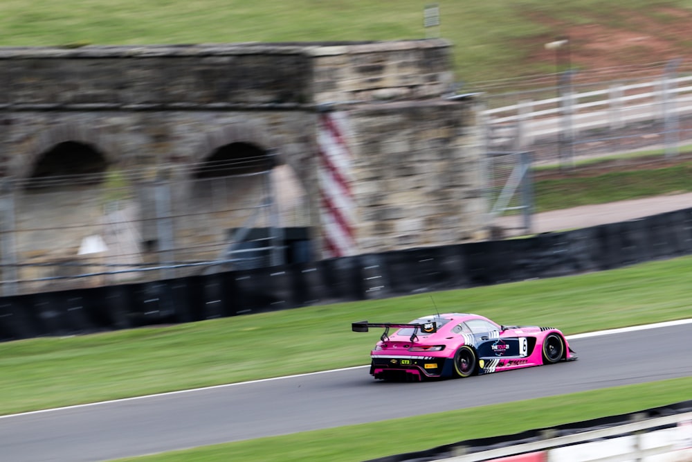 Un coche de carreras rosa conduciendo por una pista de carreras