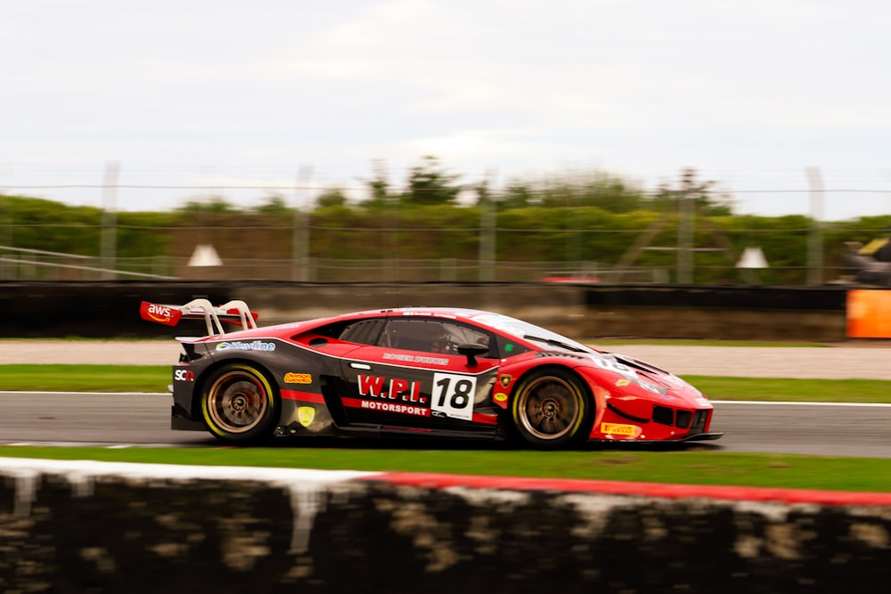 a red race car driving down a race track