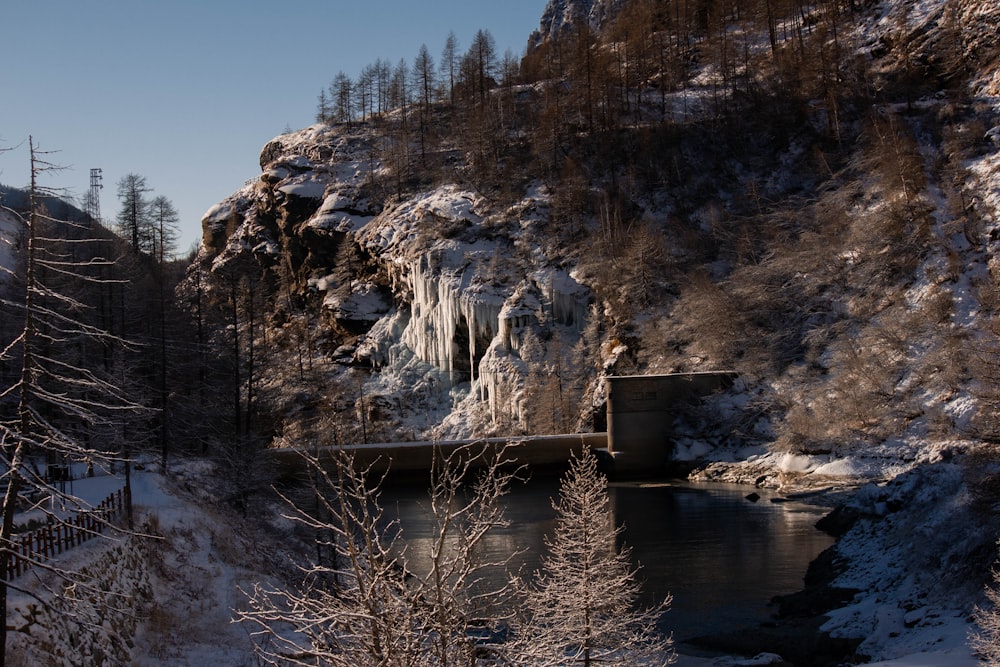 a snowy landscape with a waterfall and a bridge