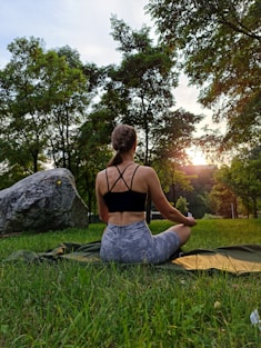 a woman sitting on the grass doing yoga