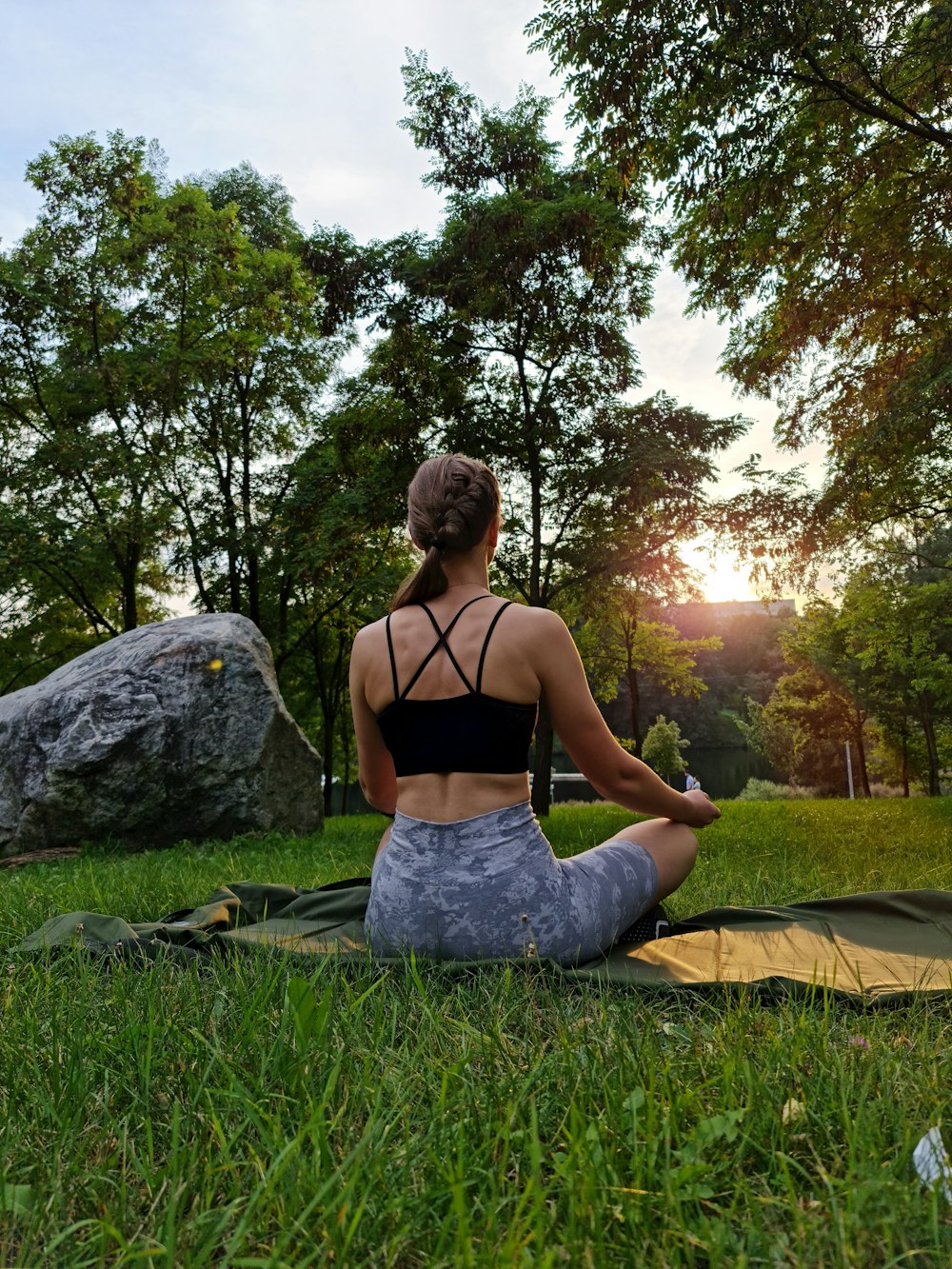 a woman sitting on the grass doing yoga