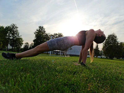 a woman is doing a push up in the grass