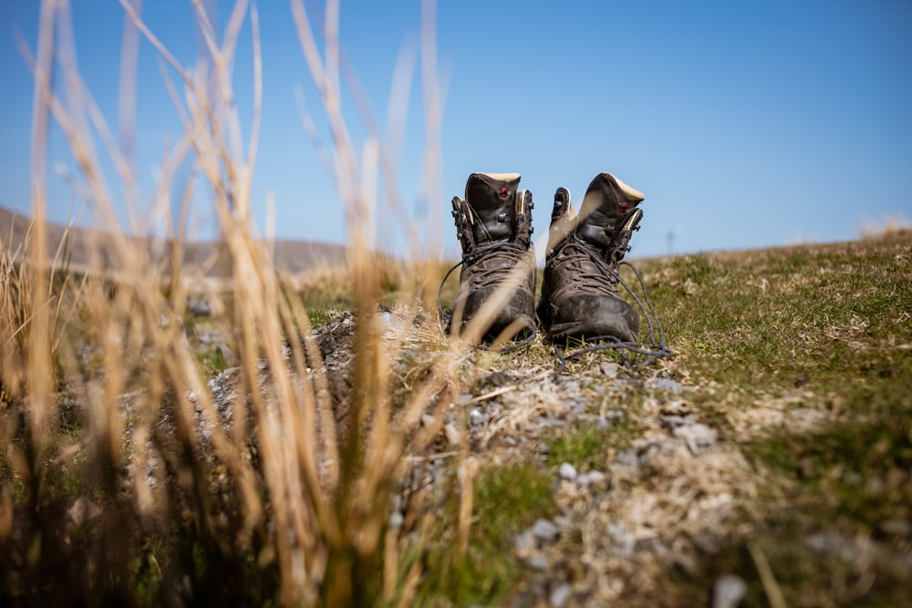 a pair of boots sitting on top of a grass covered field