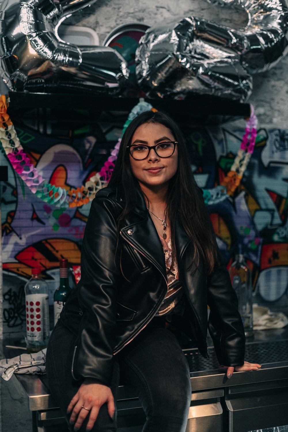 a woman in a black leather jacket and glasses