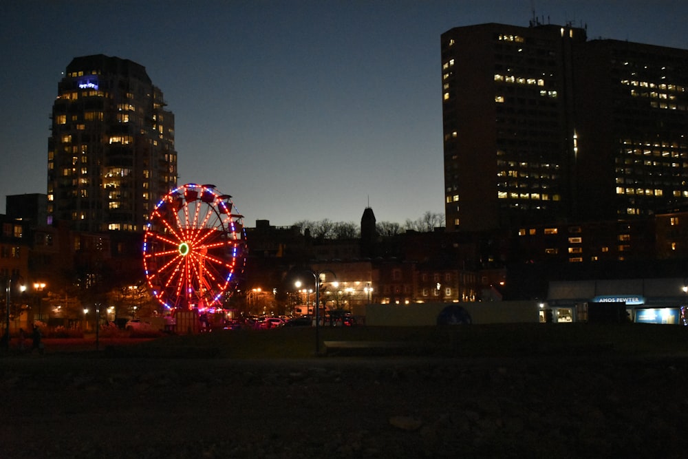 a ferris wheel lit up at night in a city