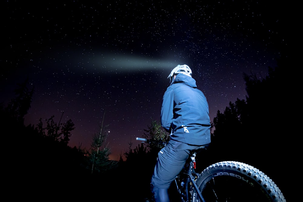 Un hombre montando en bicicleta por la noche con las estrellas en el cielo