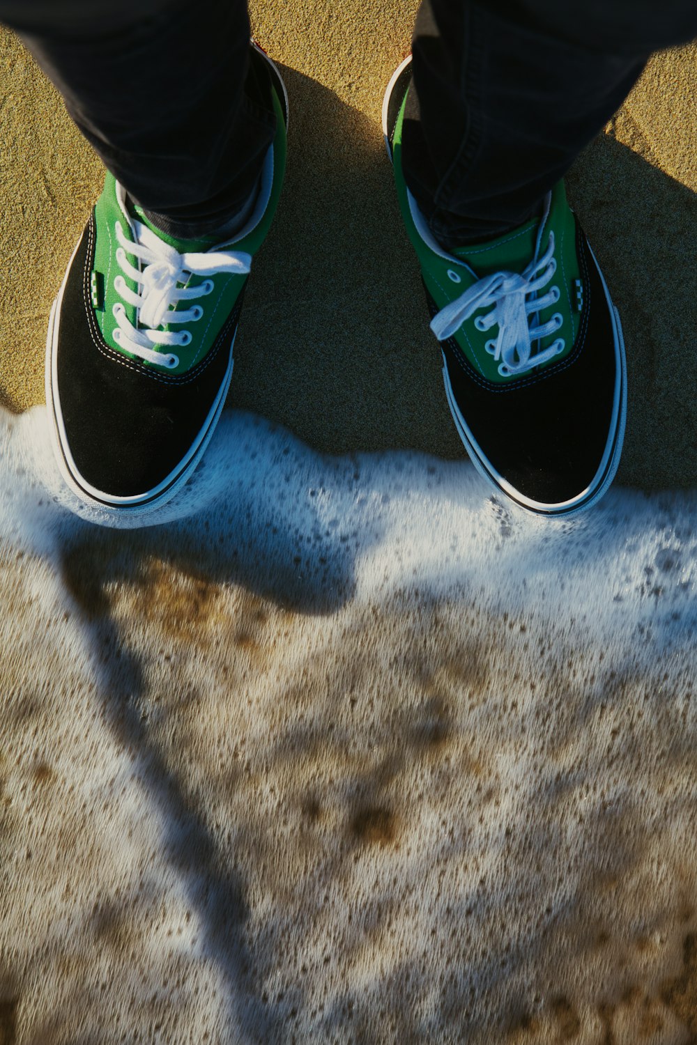 a person wearing green and white shoes standing on a sidewalk