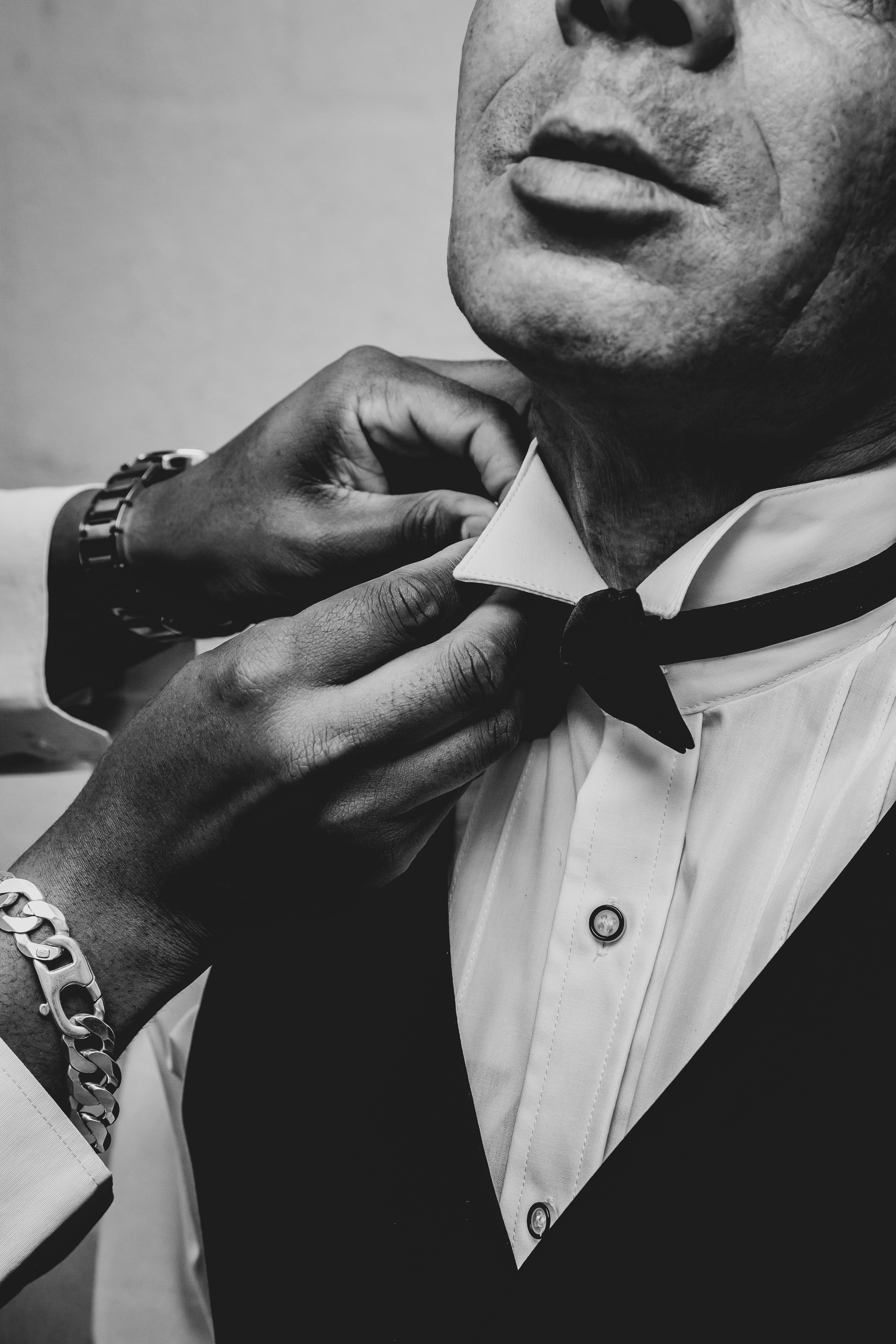 a man in a tuxedo adjusts his bow tie