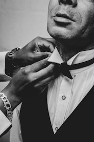 a man in a tuxedo adjusts his bow tie