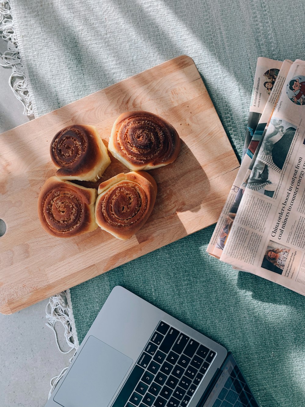 a wooden cutting board topped with pastries next to a laptop
