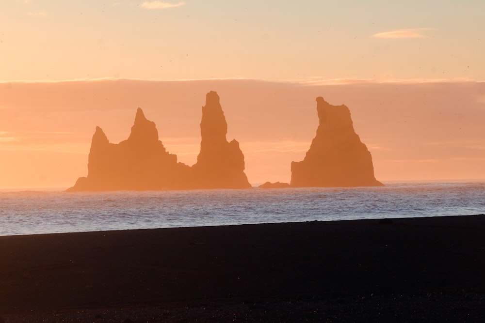 a group of rocks in the ocean at sunset