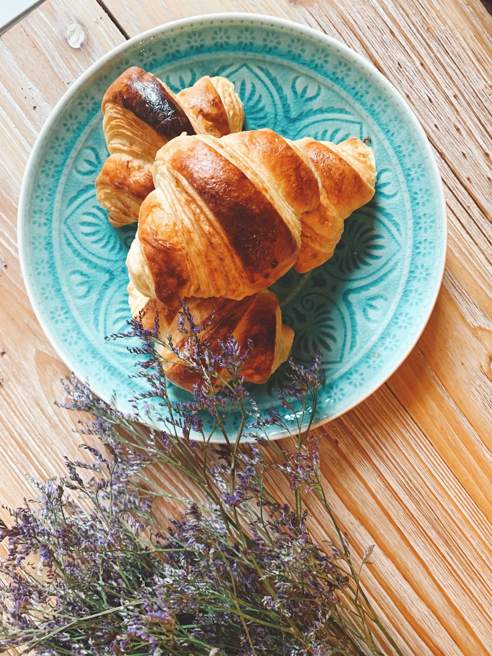 a plate of croissants and lavender on a wooden table