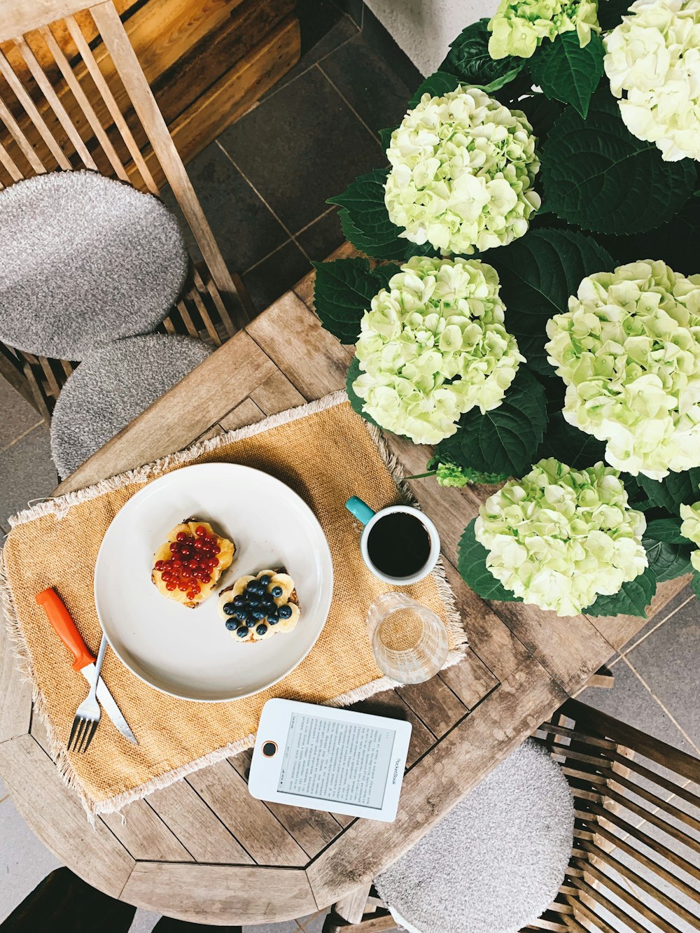 a white plate topped with fruit next to a cup of coffee