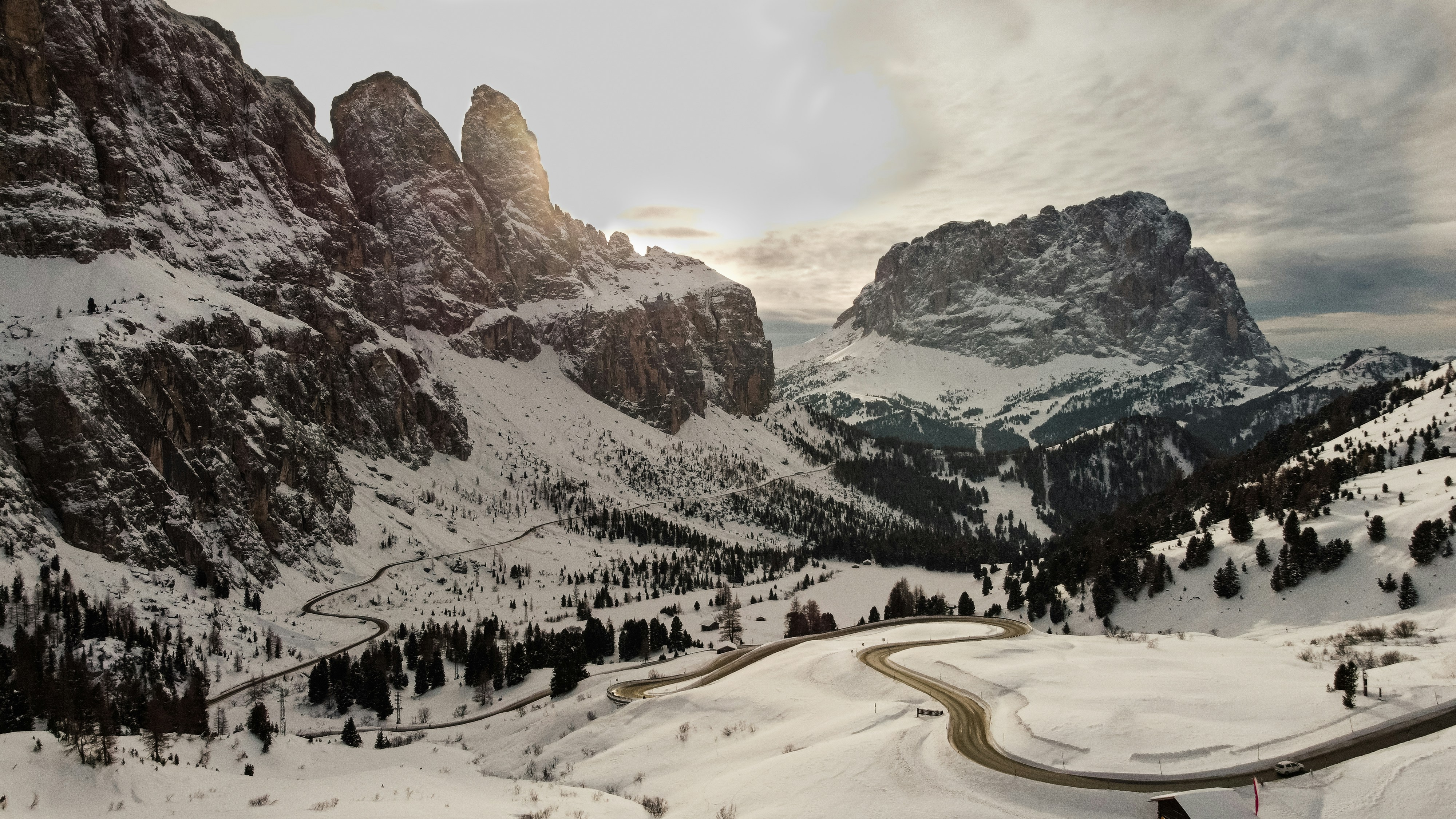 a winding road surrounded by snow covered mountains