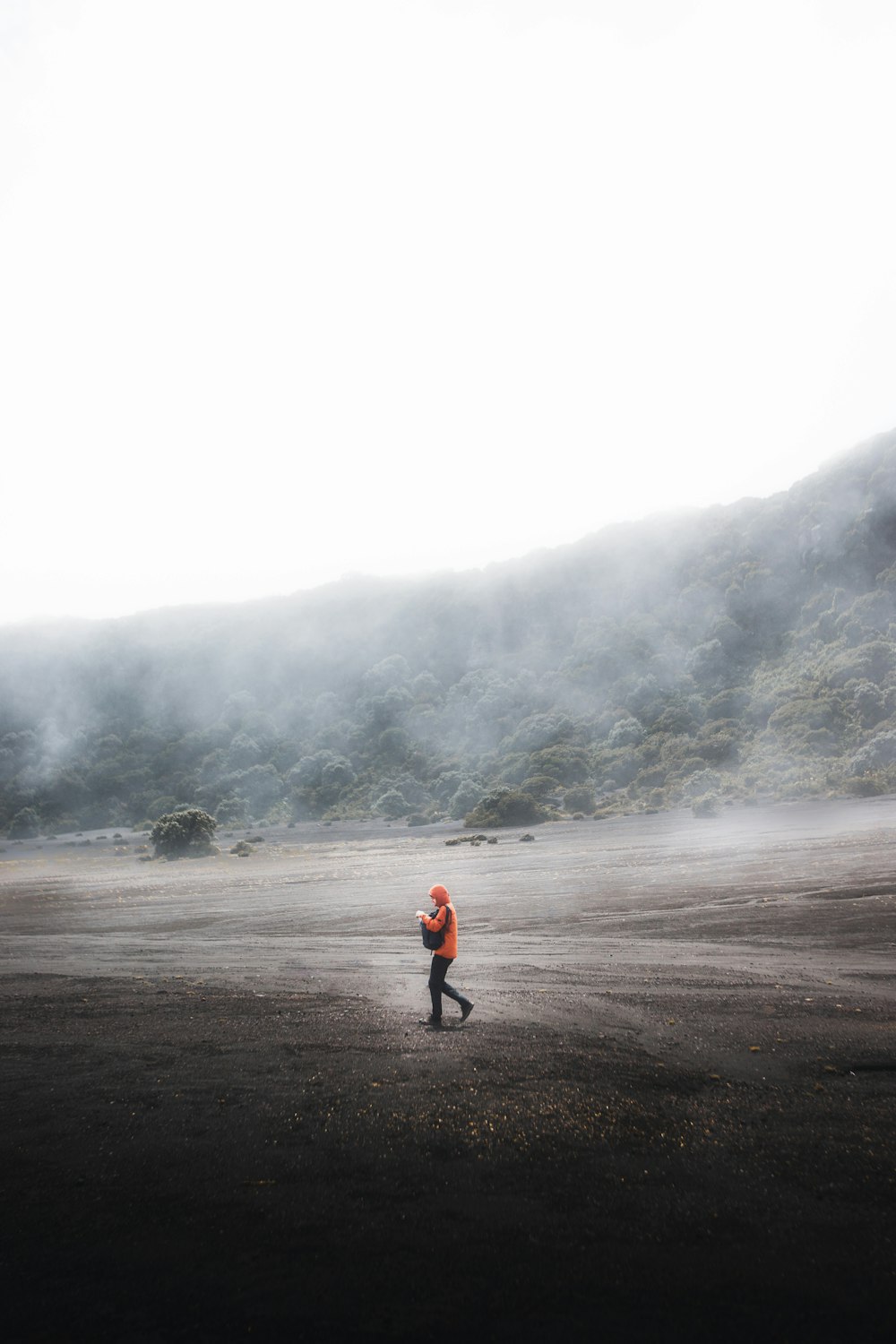 a man in an orange jacket is flying a kite