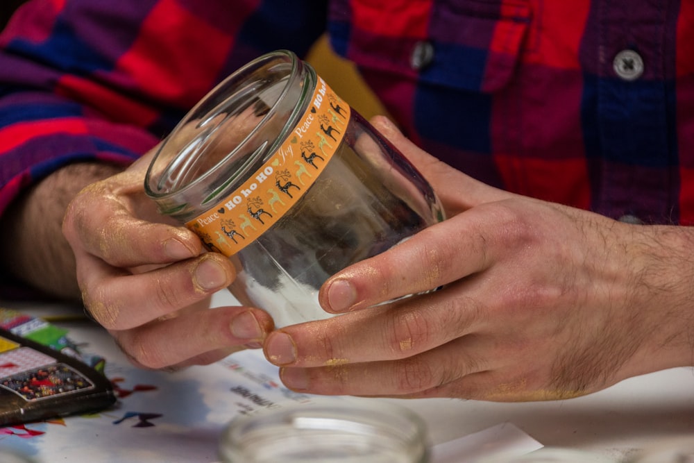 a man is holding a jar with a measuring tape on it