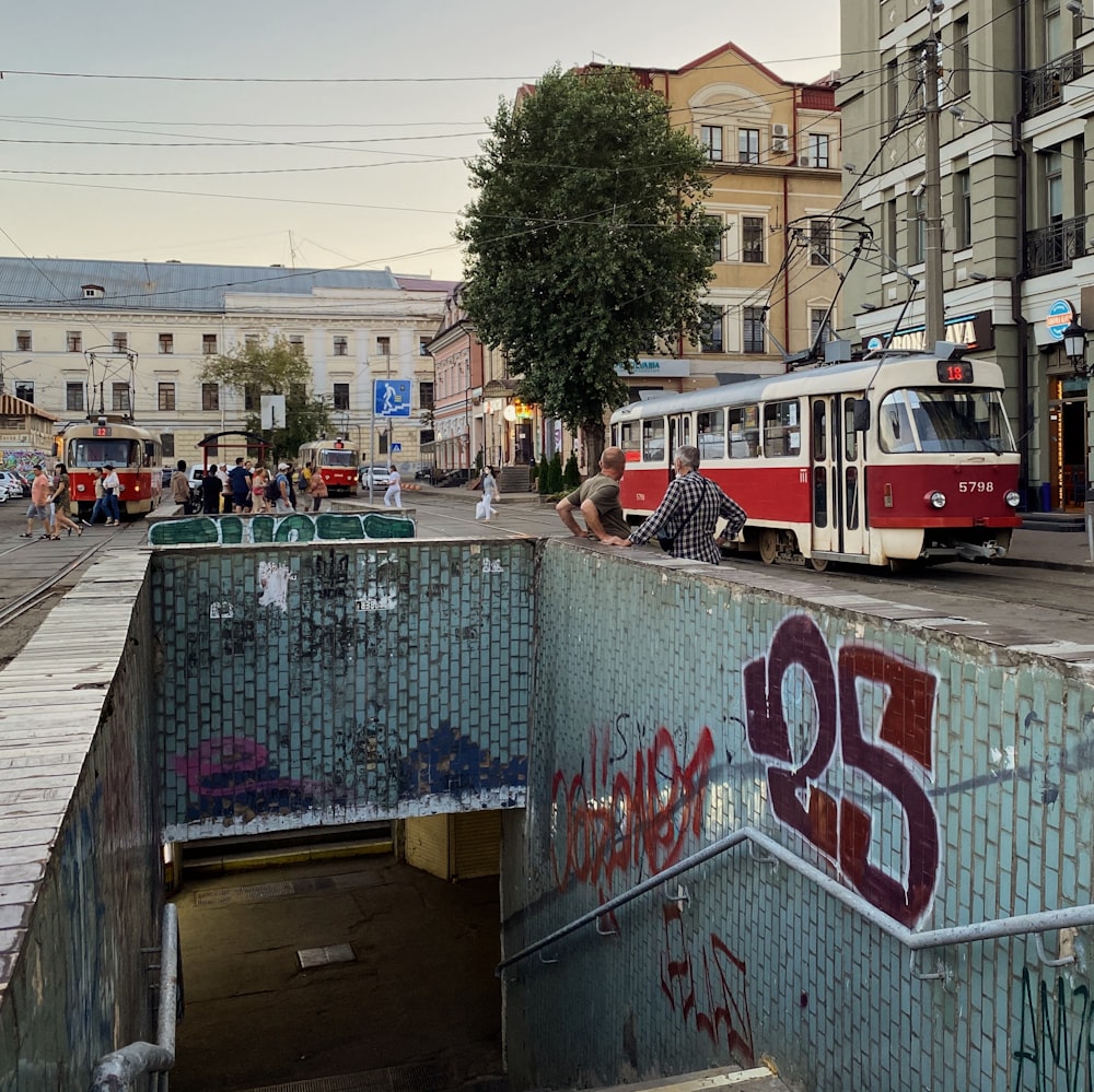 a red and white bus driving down a street next to tall buildings