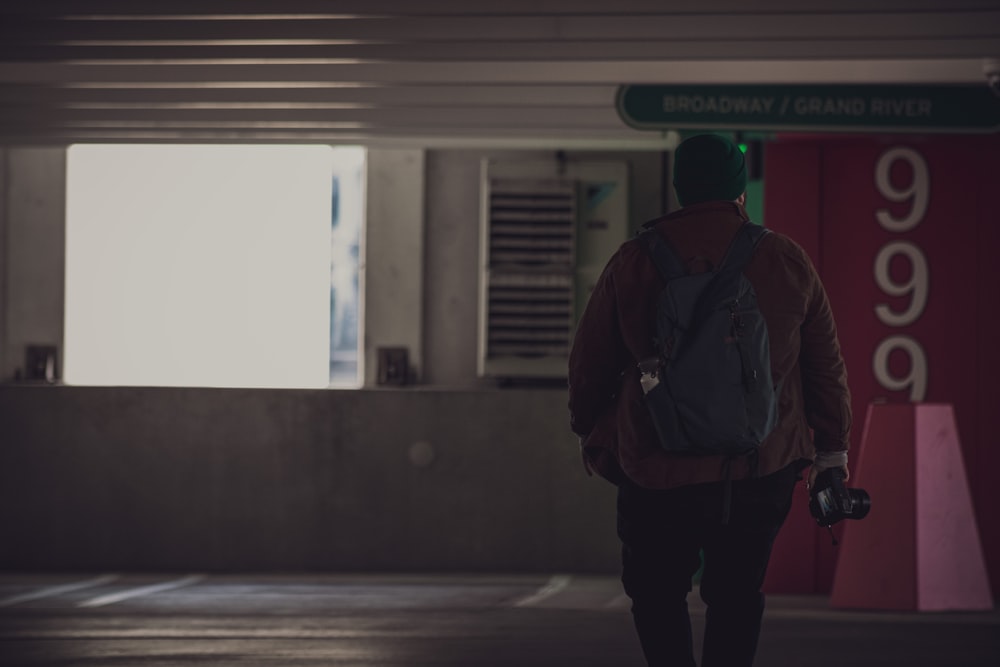 a man with a backpack and camera walking in a parking garage
