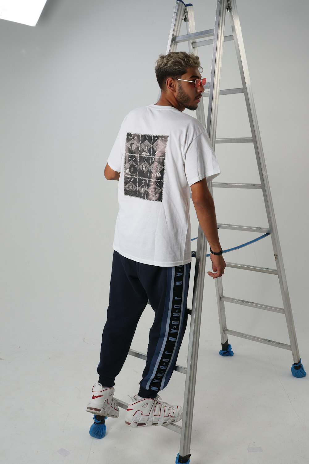 a man standing on a ladder wearing a white t - shirt