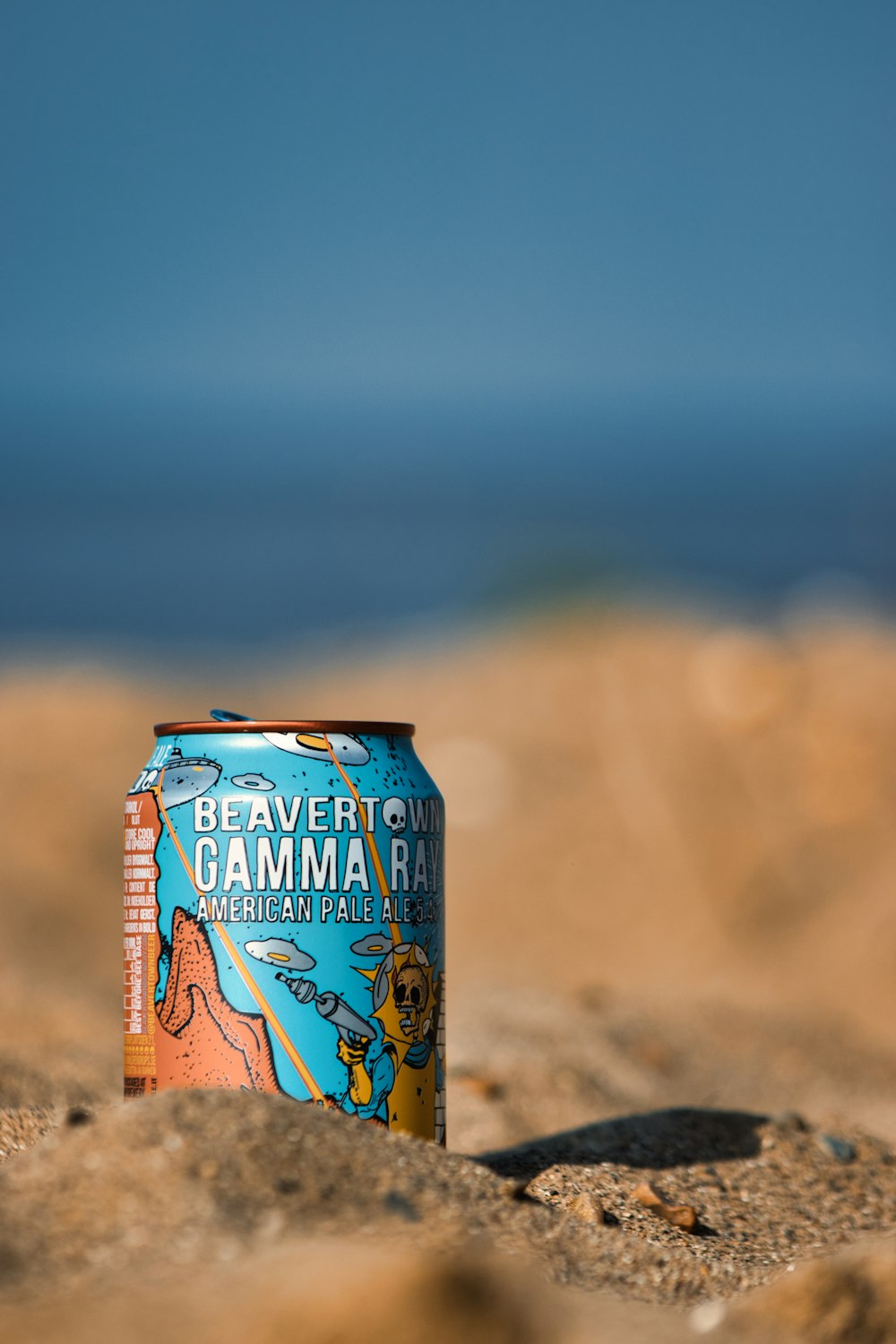 una lattina di birra seduta in cima a una spiaggia sabbiosa