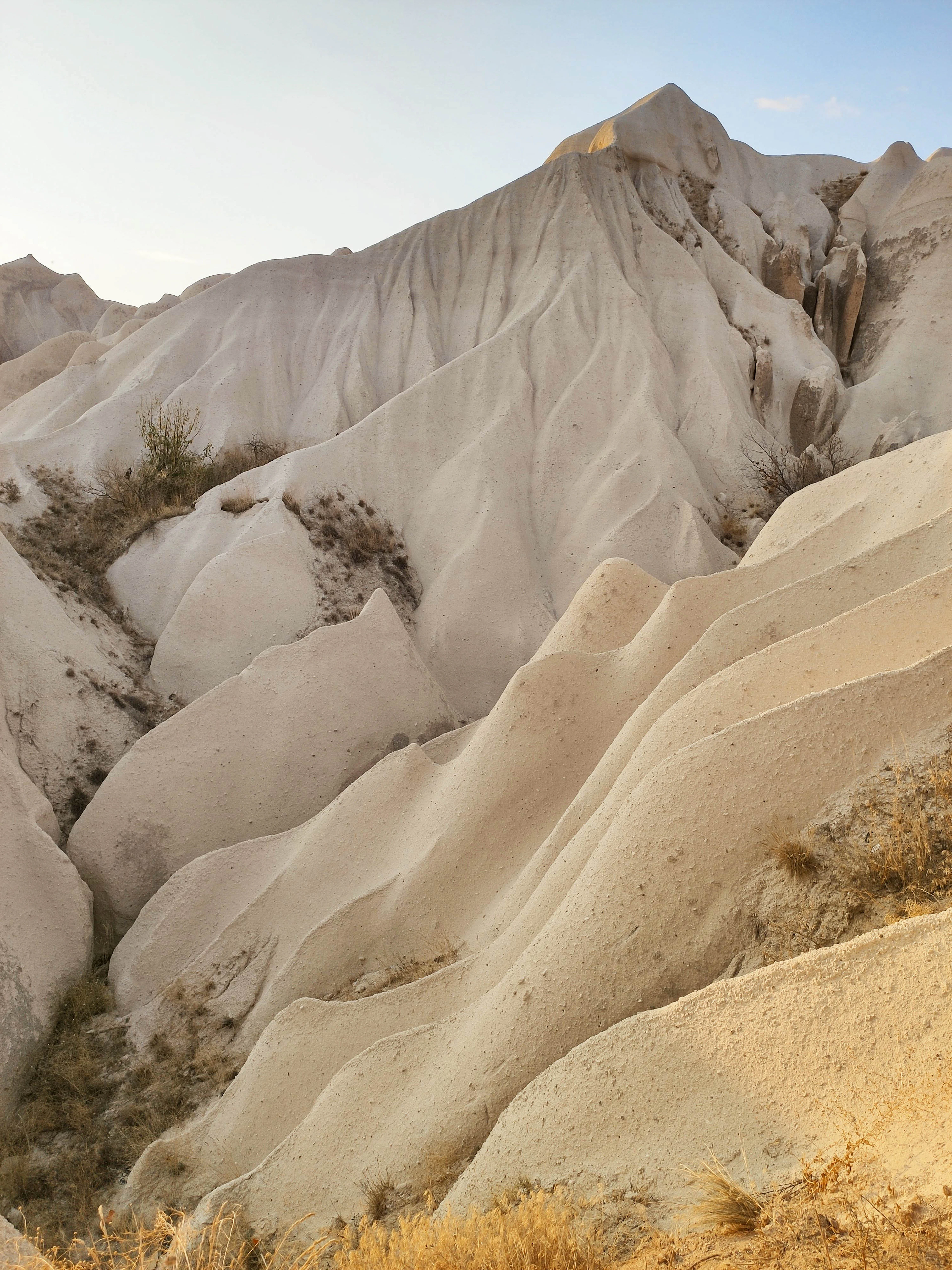 Golden evening light rakes across the sculpted folds of a Cappadocia rock ridge.