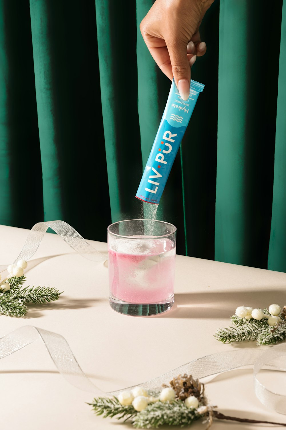 a person holding a tube of toothpaste in a glass