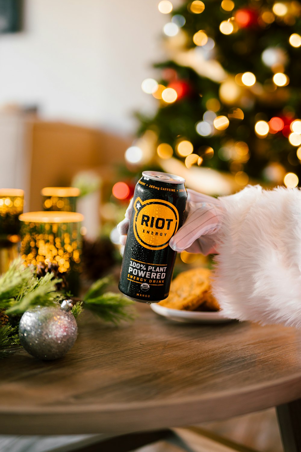 a person holding a can of root beer in front of a christmas tree