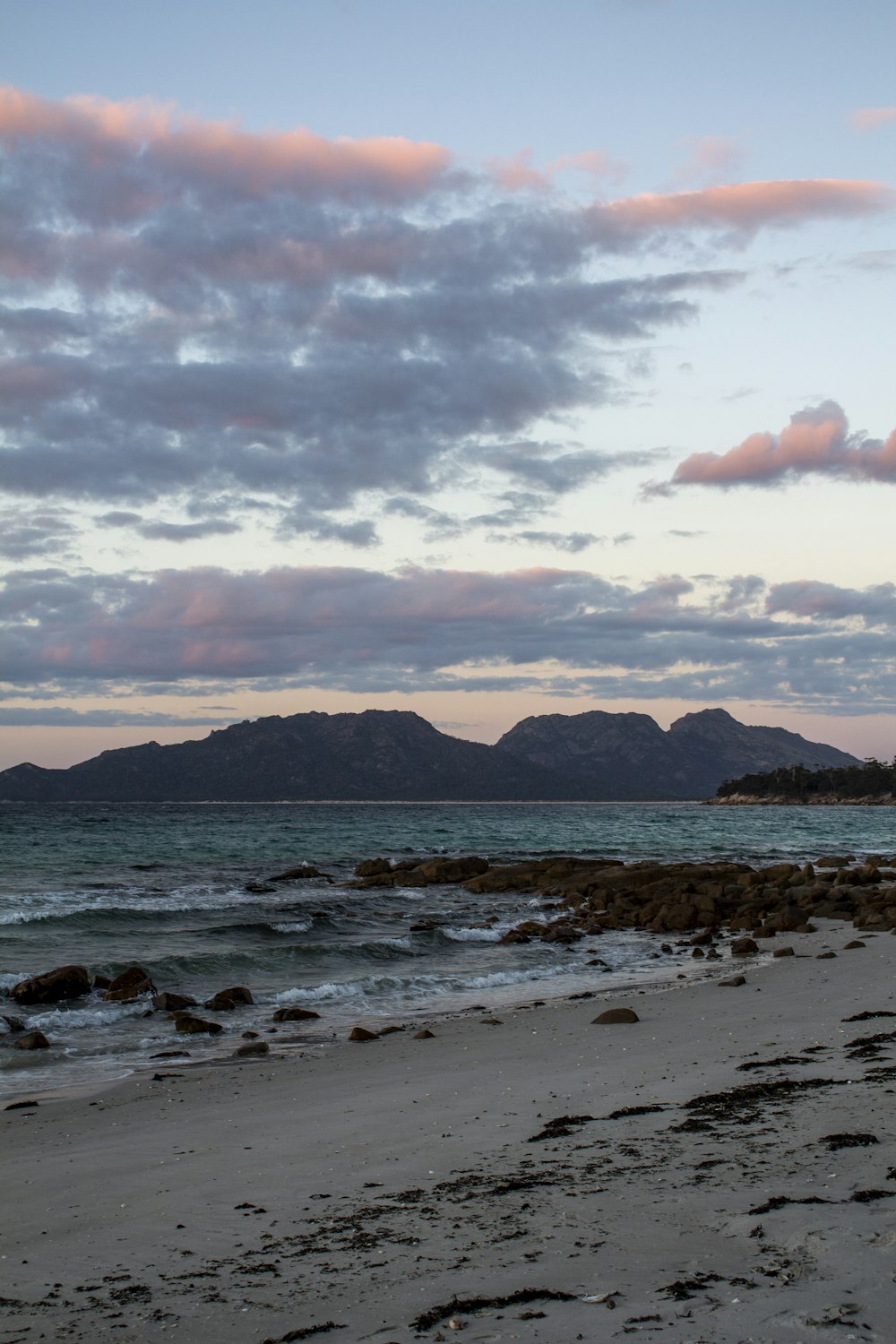 a beach with a body of water and mountains in the distance