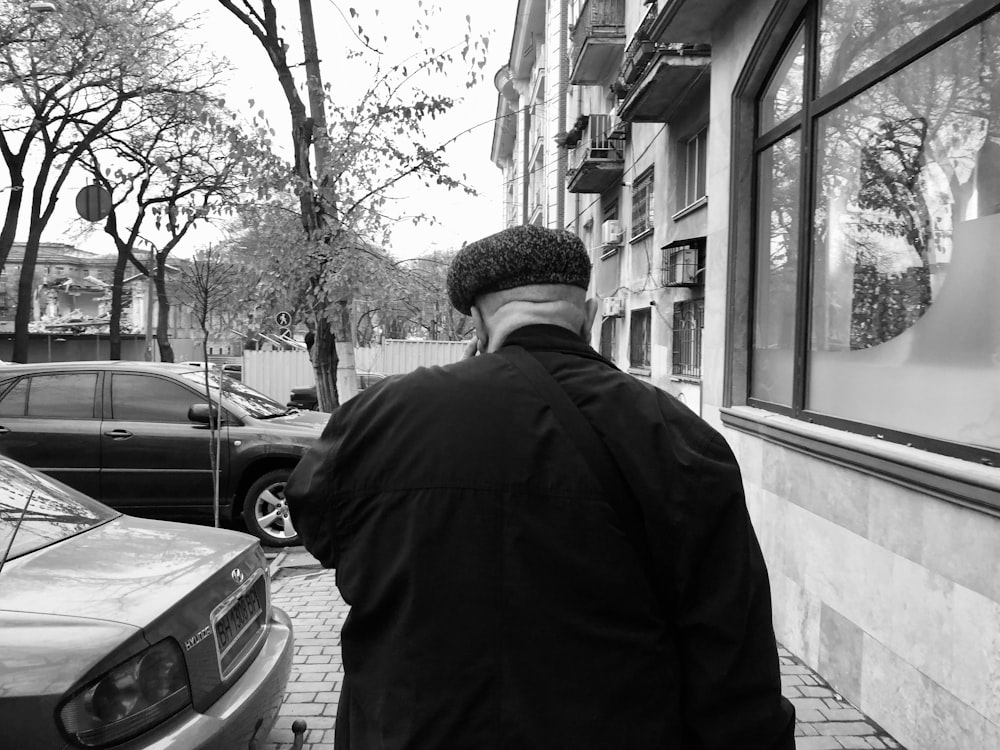 a man walking down a sidewalk next to parked cars