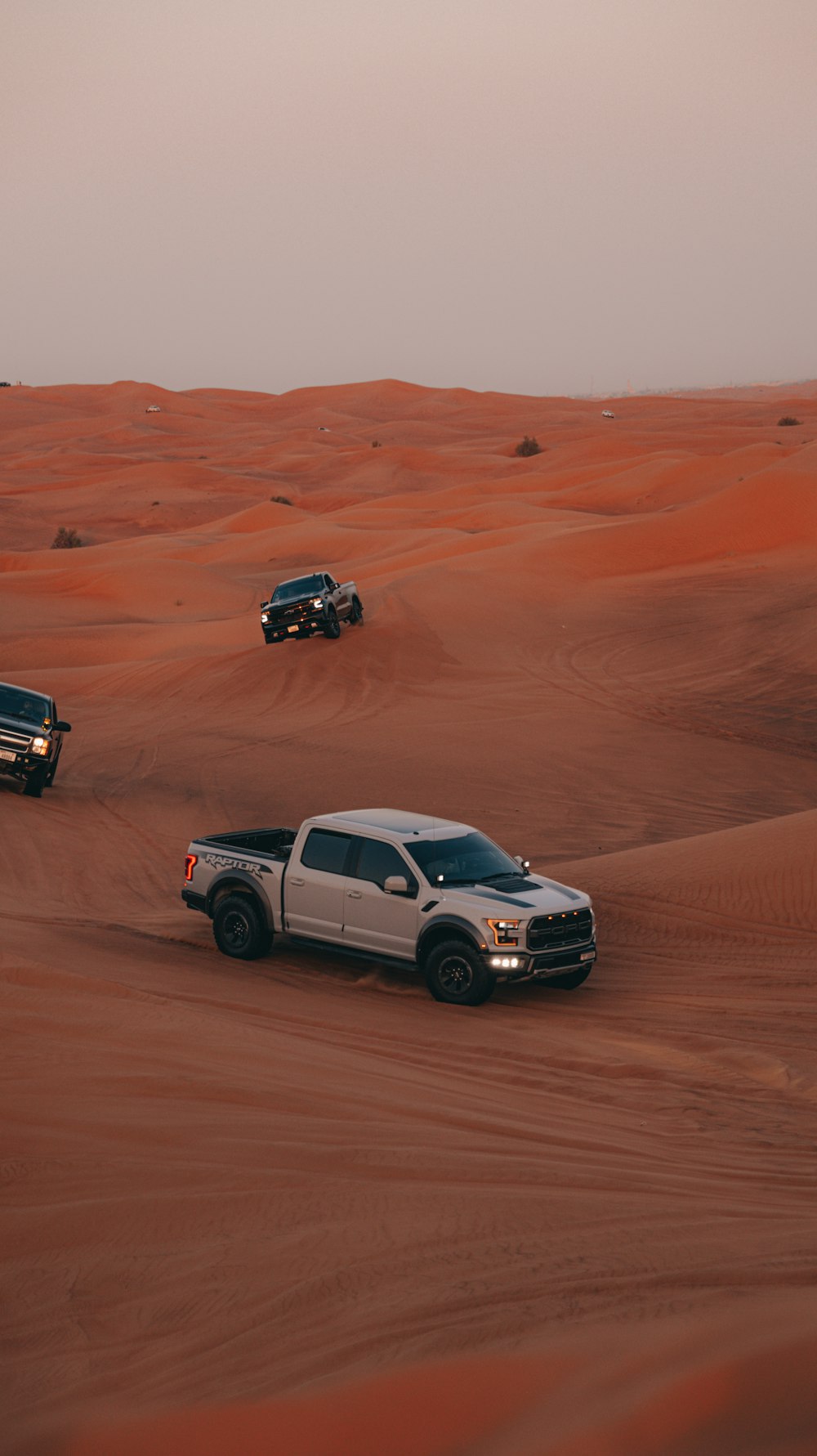 a couple of trucks driving through a desert