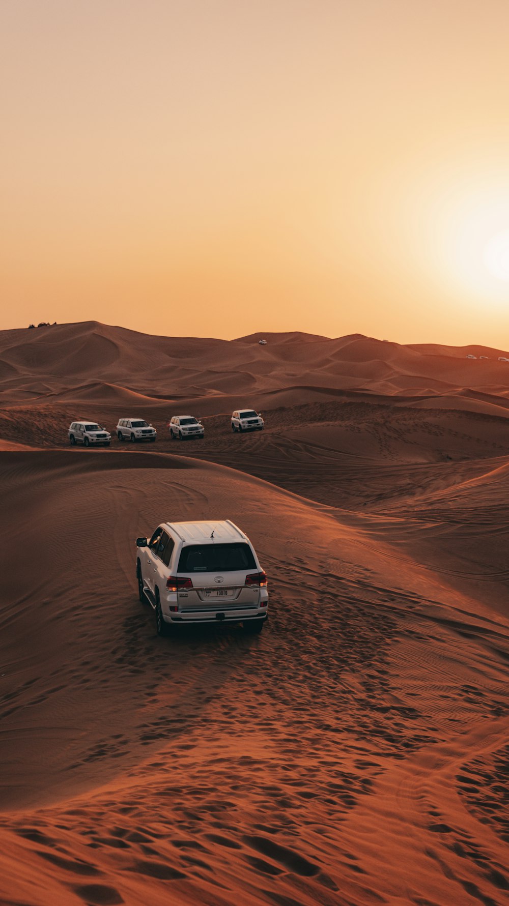 a white car driving through the desert at sunset