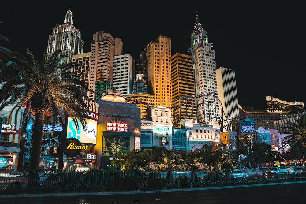 a city at night with tall buildings and palm trees