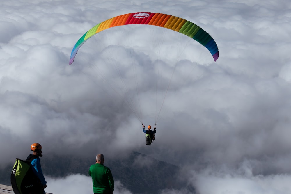 two people are parasailing in the sky above the clouds