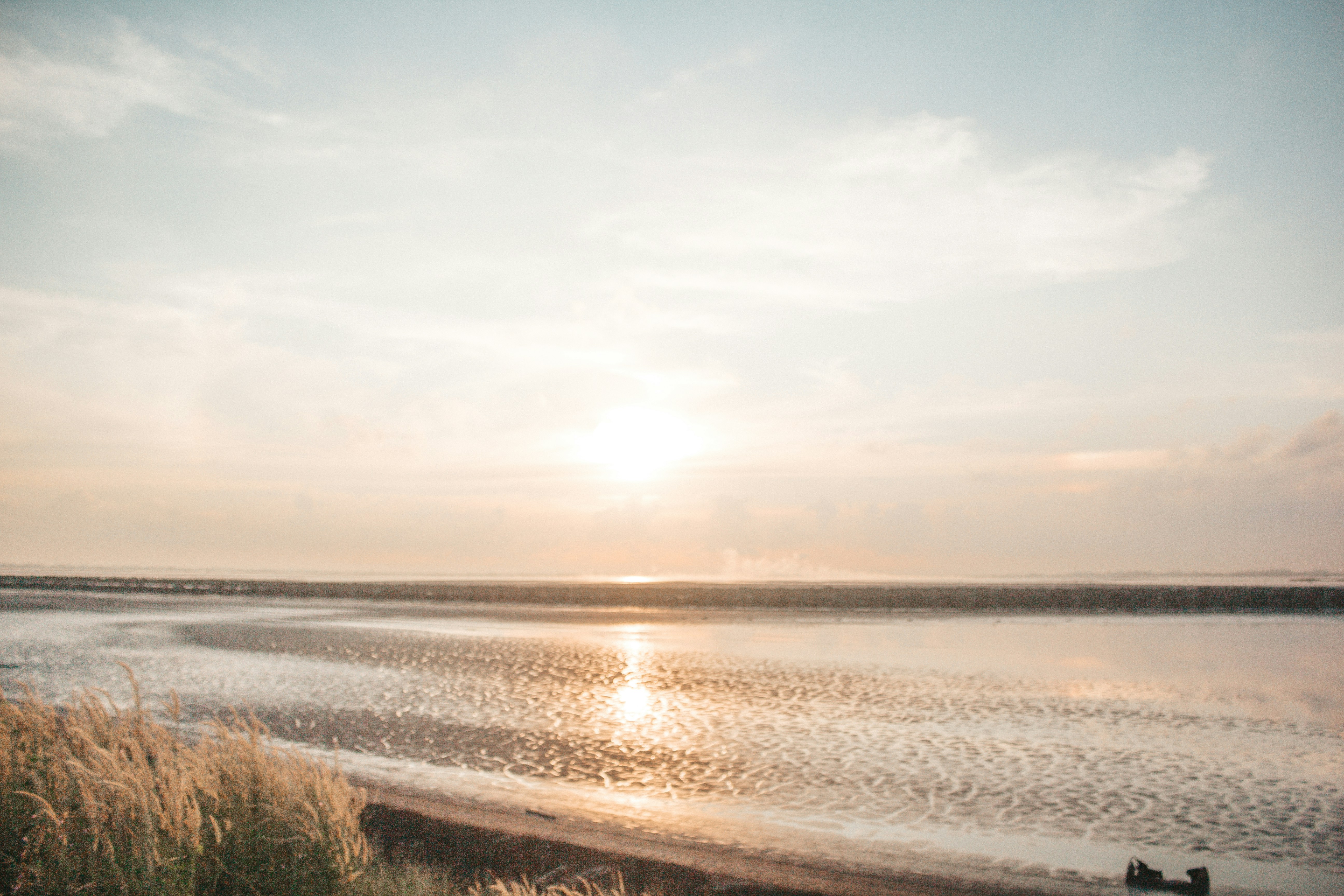 the sun is setting over the water at the beach