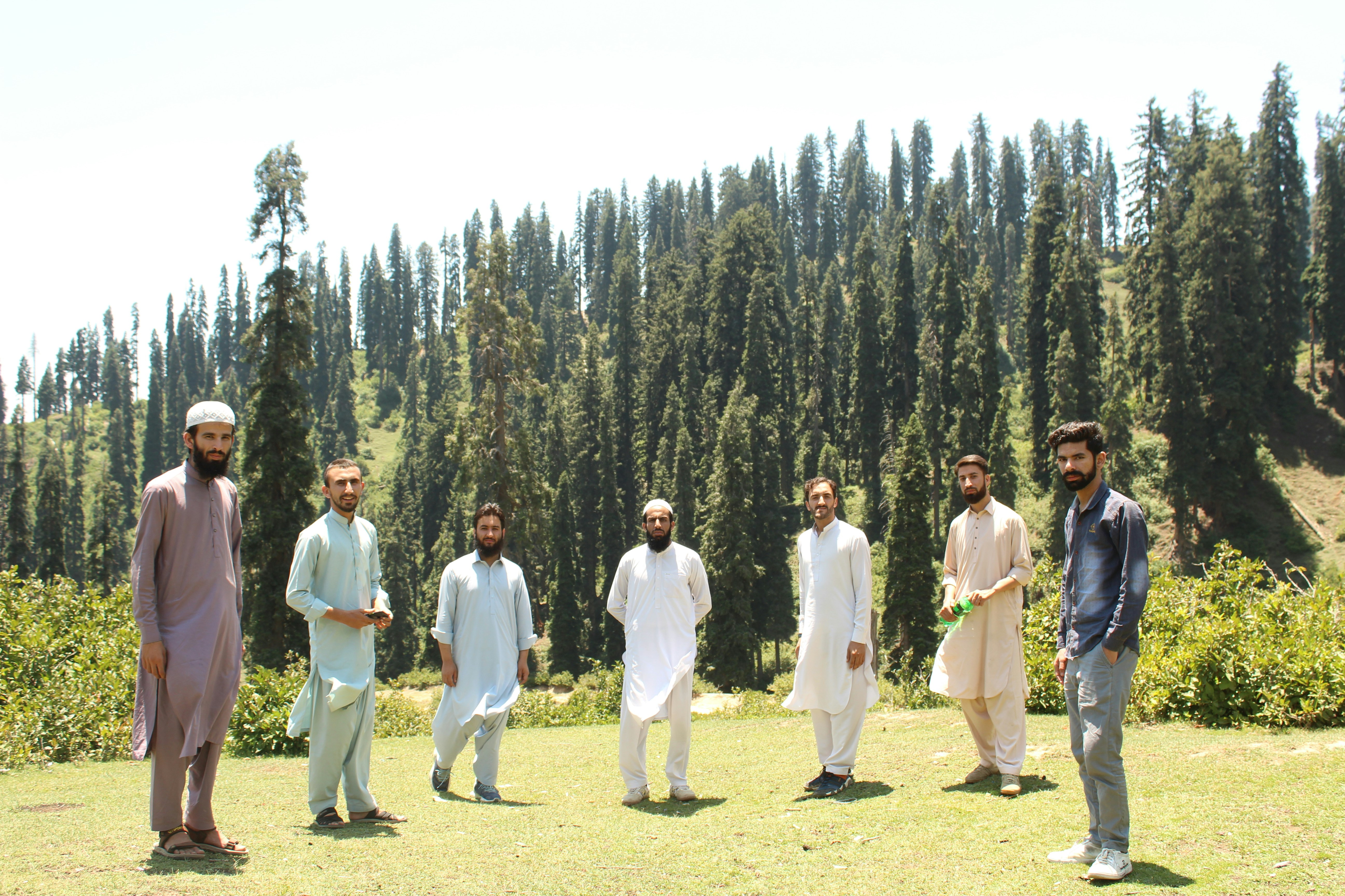a group of men standing on top of a lush green field