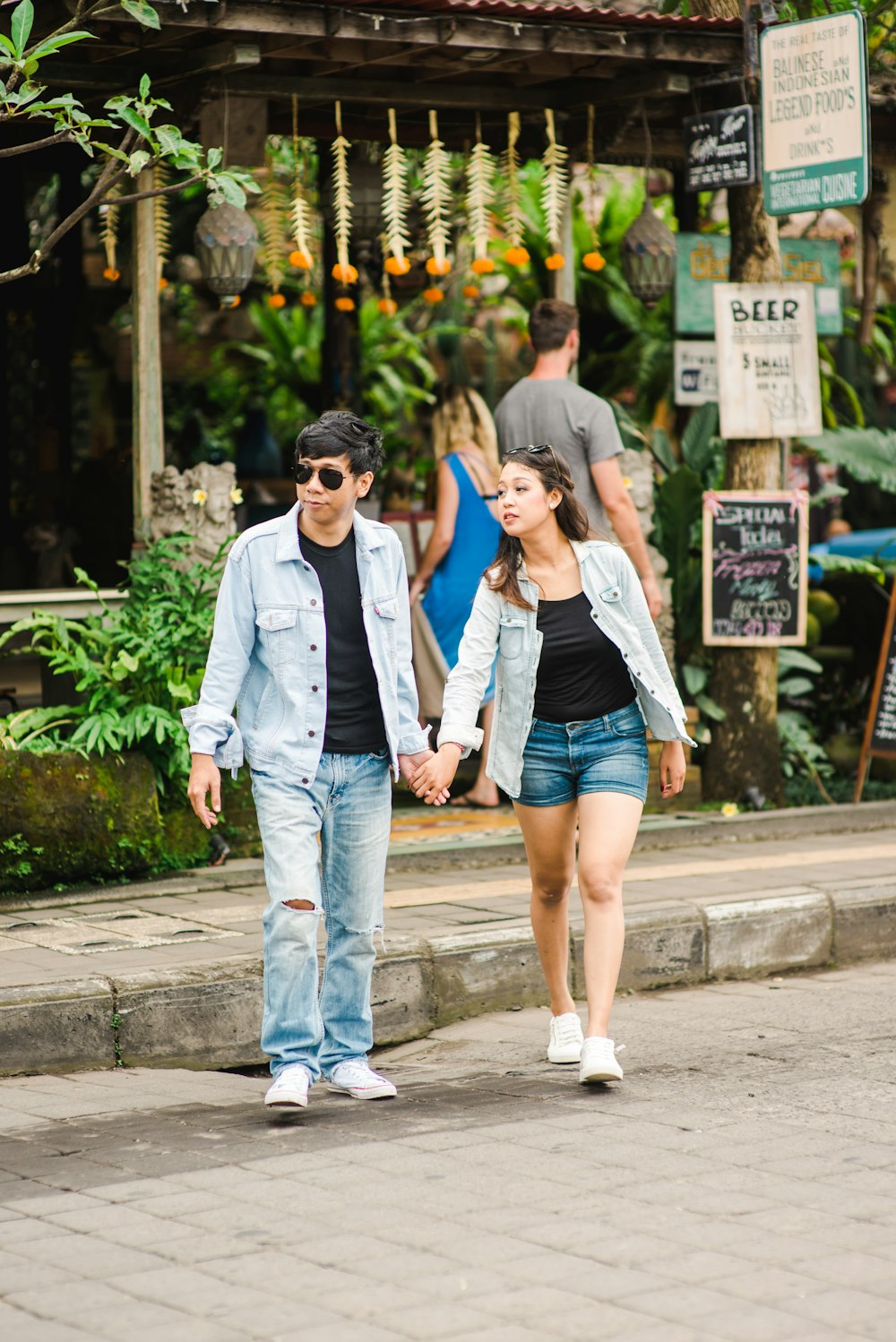 a man and woman walking down a street holding hands