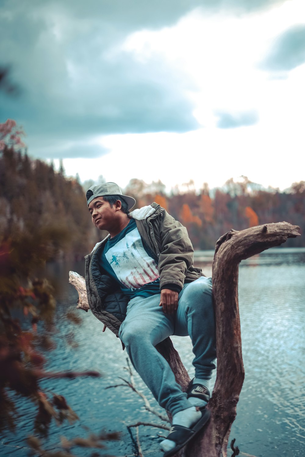 a man sitting on a tree branch in front of a body of water