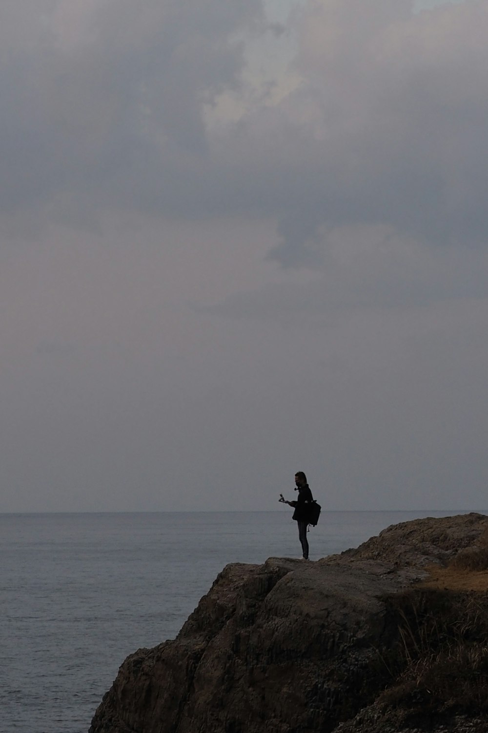 a person standing on top of a rock near the ocean