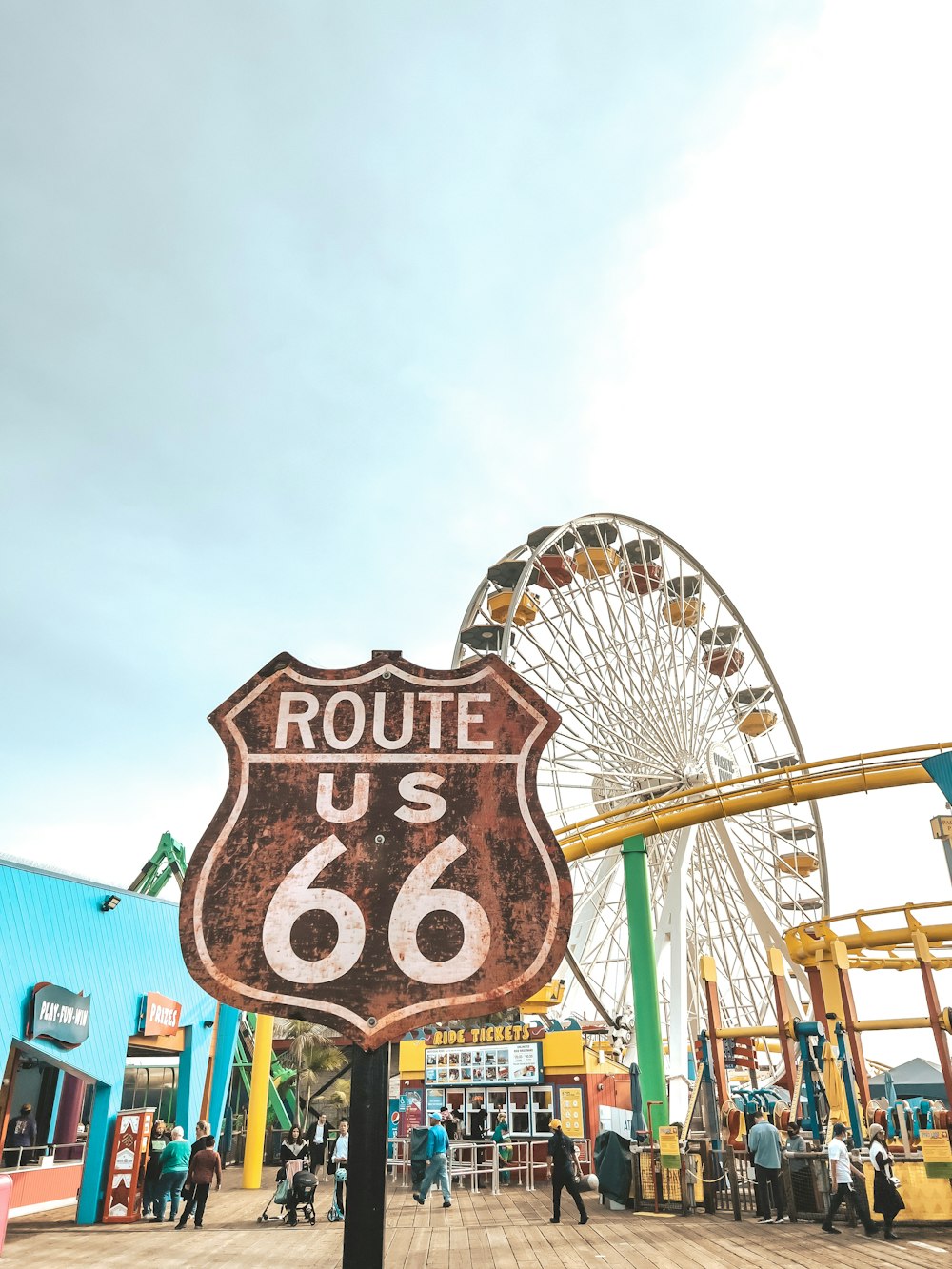 a sign that says route us 66 with a ferris wheel in the background