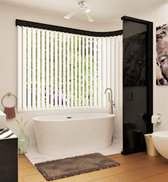 a white bath tub sitting next to a toilet under a window