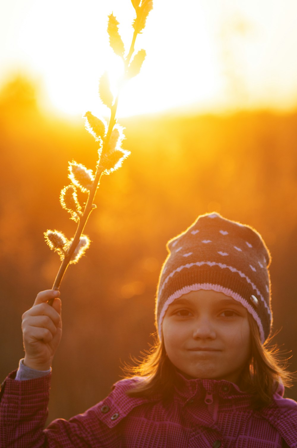 a young girl holding a flower in front of the sun