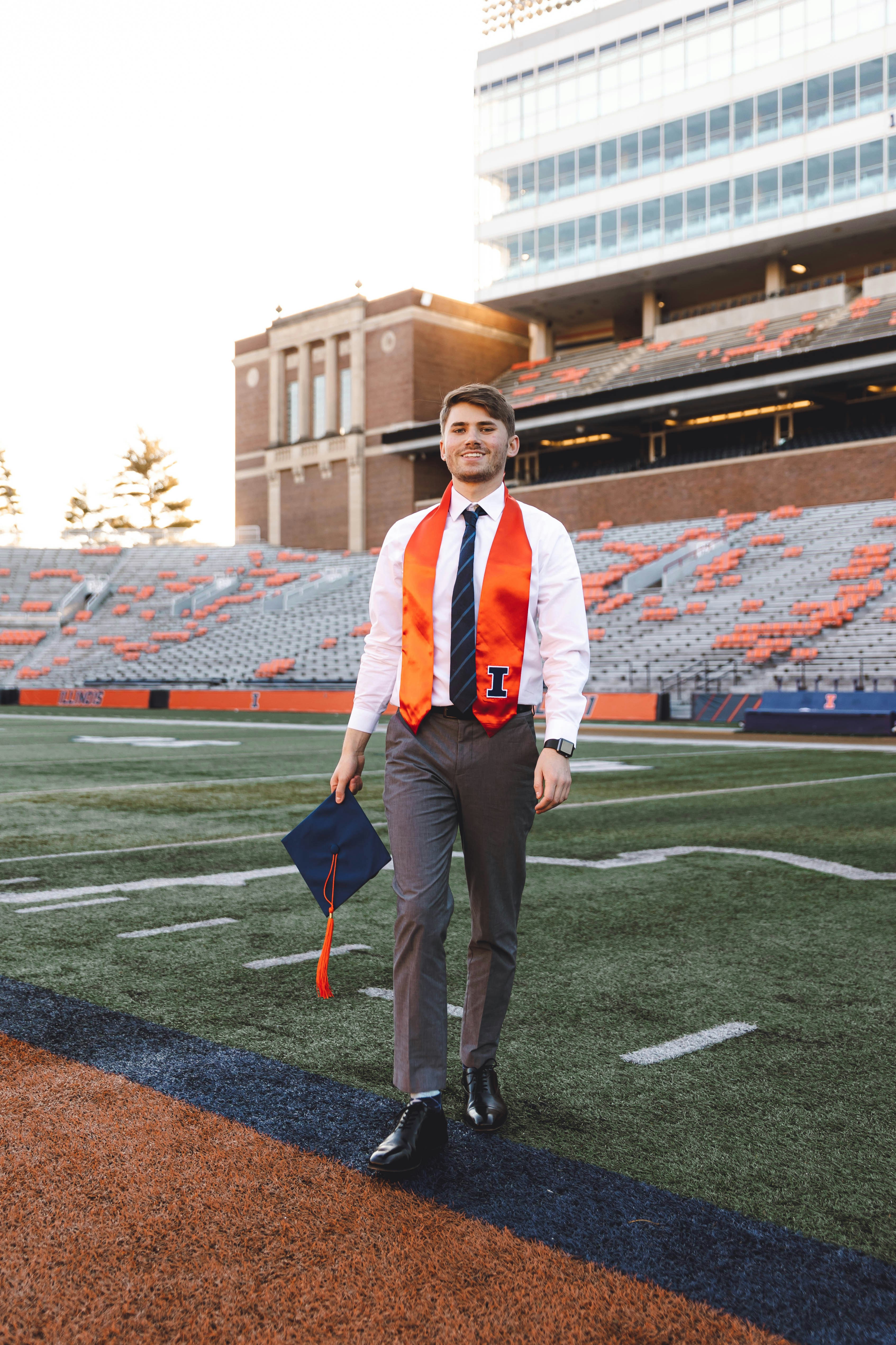 Un uomo in un giubbotto arancione e cravatta che cammina su un campo di calcio