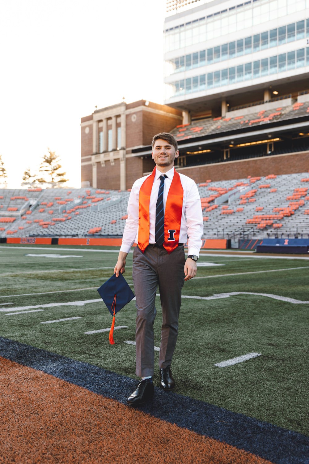 a man in an orange vest and tie walking on a football field