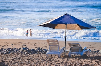 two chairs and an umbrella on a beach