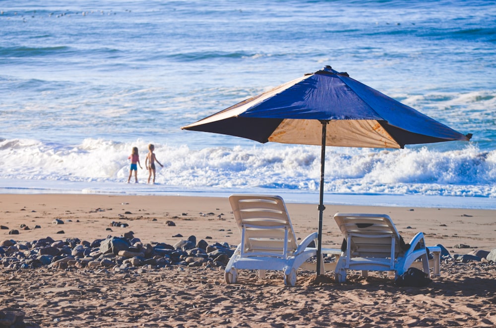 two chairs and an umbrella on a beach