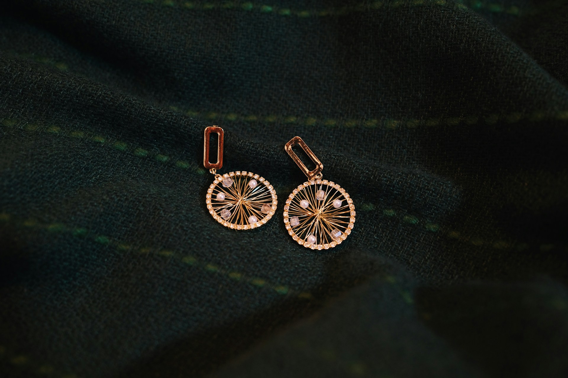 a pair of earrings sitting on top of a green cloth