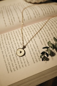 A close-up of a heart-shaped pendant resting on an open book.
