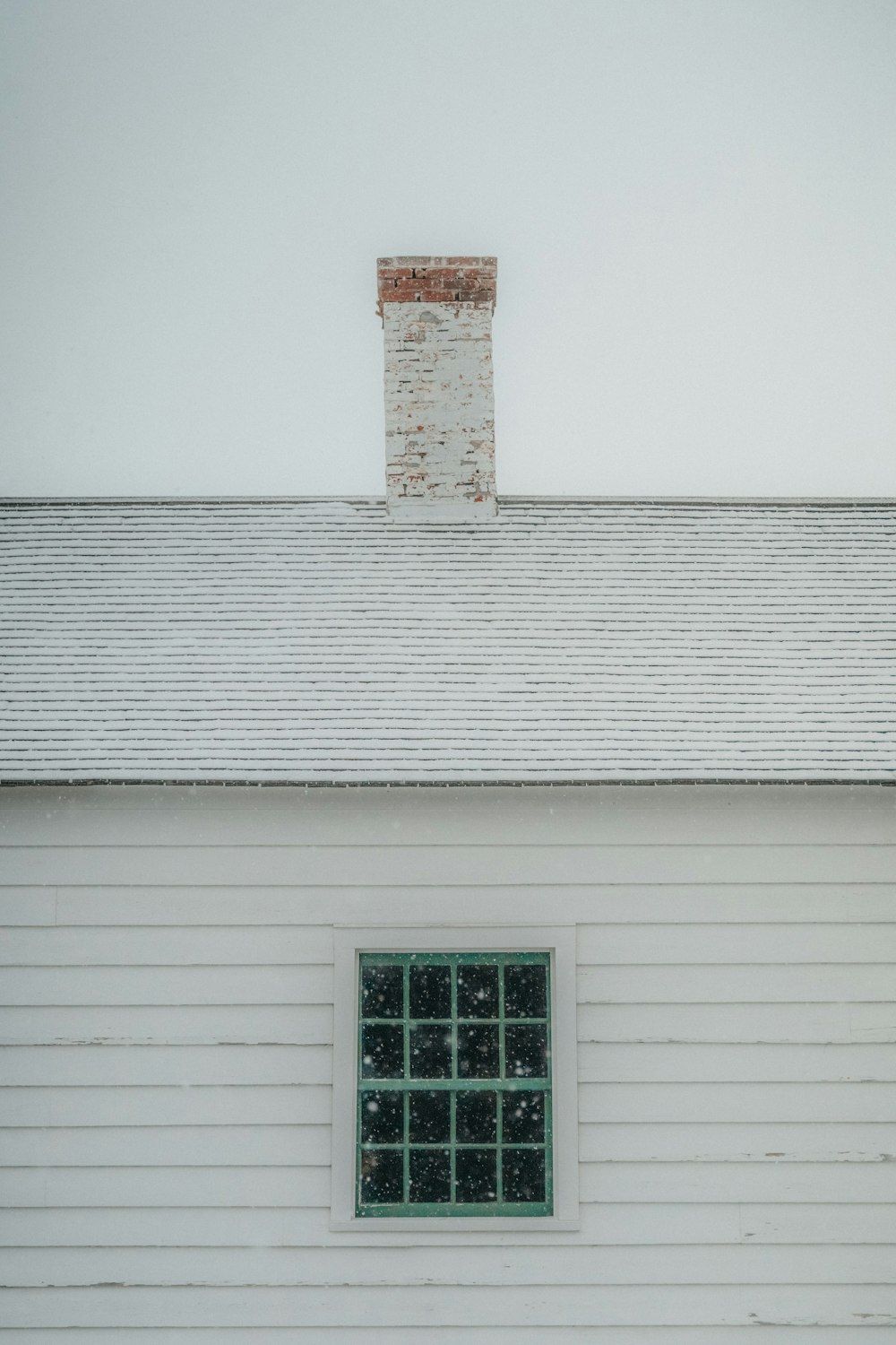 a white building with a window and a brick chimney