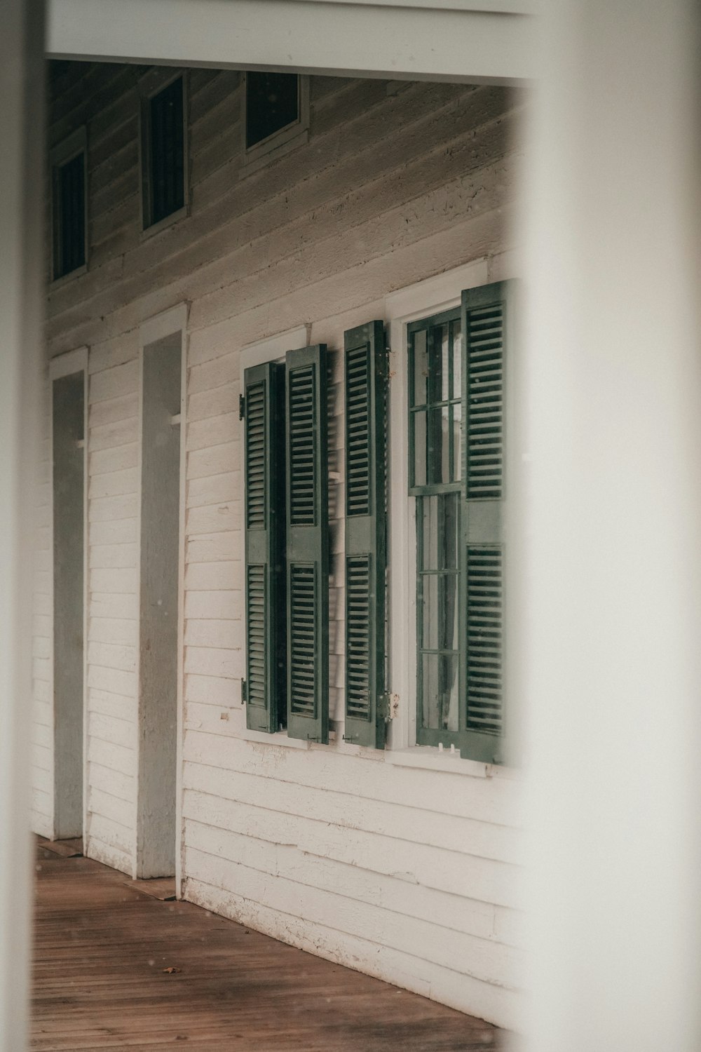 a white house with green shutters and a wooden floor