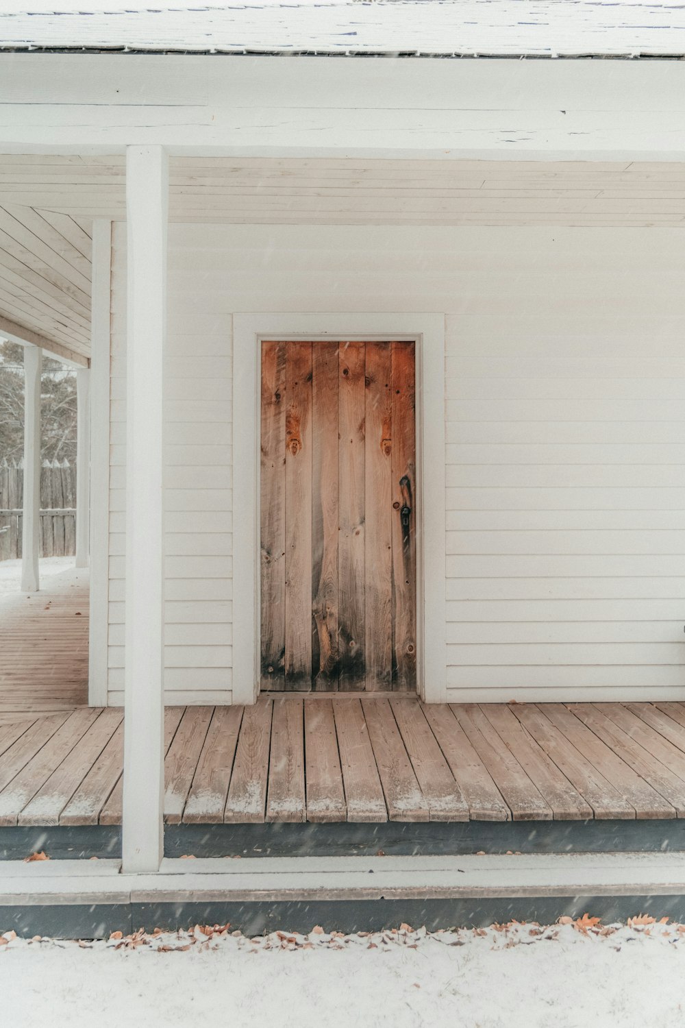 une maison blanche avec une porte en bois et un porche